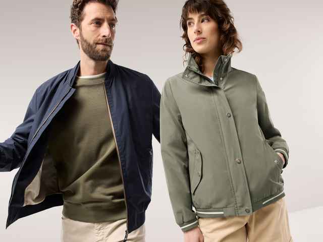 Ein Mann trägt einen Blouson in Marine, darunter ein Sweat-Shirt in Khaki, daneben Frau in der Blousonjacke Baumwollmix in Khaki.
