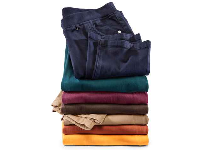 Stapel aus sechs gefalteten Chinos in verschiedenen Farben: Dunkelblau, Grün, Rotbraun, Dunkelbraun, Beige und Orange vor weißem Hintergrund.