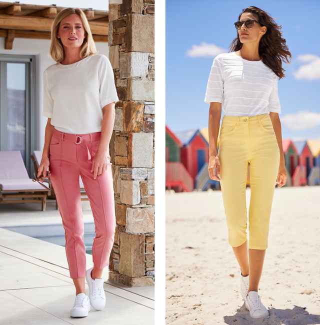 Zwei Frauen in weißen Oberteilen und bunten Hosen, eine in Rosa auf der Terrasse, die andere in Gelb am Strand, beide tragen weiße Sneakers.