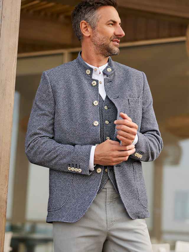 Ein Mann trägt eine blaue Strukturjacke mit passender Weste, was modern, klassisch und entspannt wirkt.
