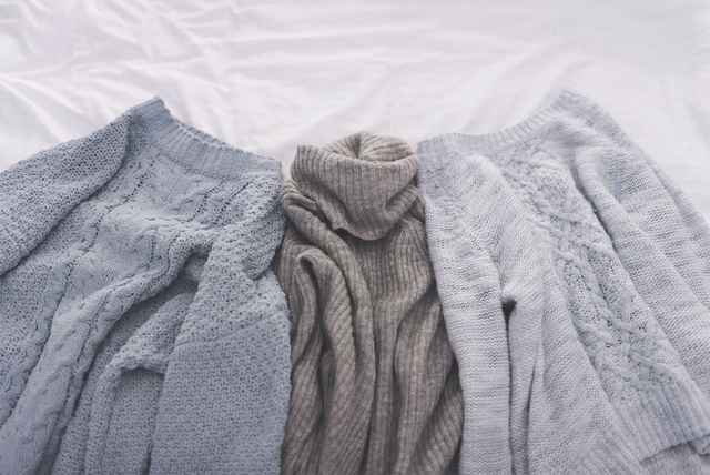 Drei liegende verschieden farbige Pullover aus Wolle.