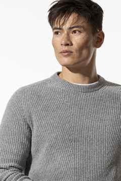 Ein Mann trägt einen Strickpullover in Grau.
