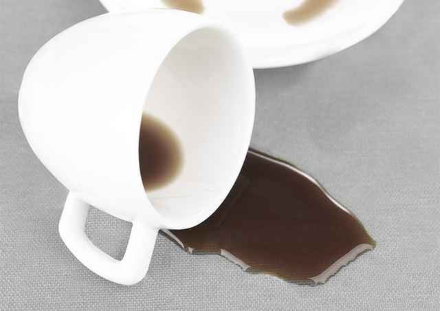 Umgekippte Kaffeetasse auf einer gepunkteten Tischdecke.