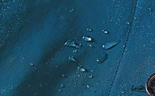 Wassertropfen auf einem dunkelblauen, wasserabweisenden Stoff.