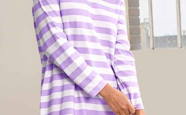 Eine Frau trägt ein Schlafshirt Sleep Well in Lavendel/Weiß.