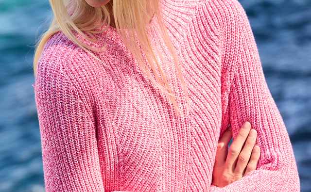 Eine Frau trägt einen Patentpullover Nahtlos in Fuchsia/Weiß.