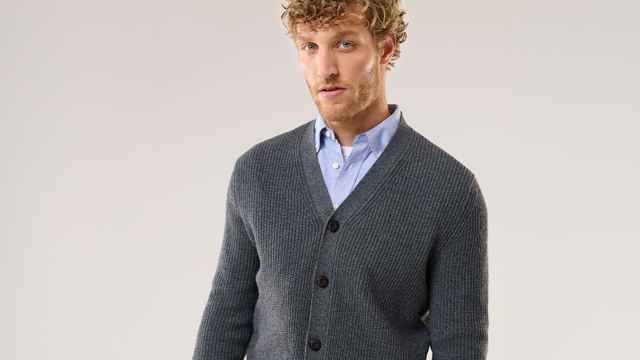 Ein Mann trägt einen Cardigan in Grau und darunter ein hellblaues Hemd.