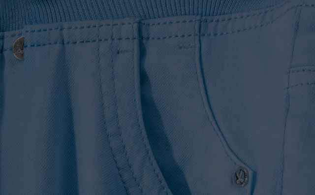 Nahaufnahme einer blauen Stoffhose mit einer in die Tasche gesteckten Hand und sichtbaren Nähten.