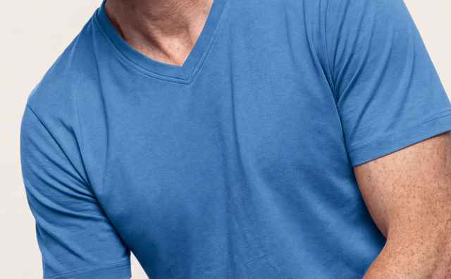 Mann mit kurzen, lockigen Haaren trägt ein blaues T-Shirt und Jeans, sitzt lässig und schaut in die Kamera.