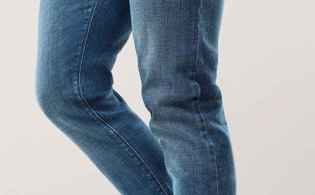 Person trägt eine blaue Jeans und weiße Sneaker.