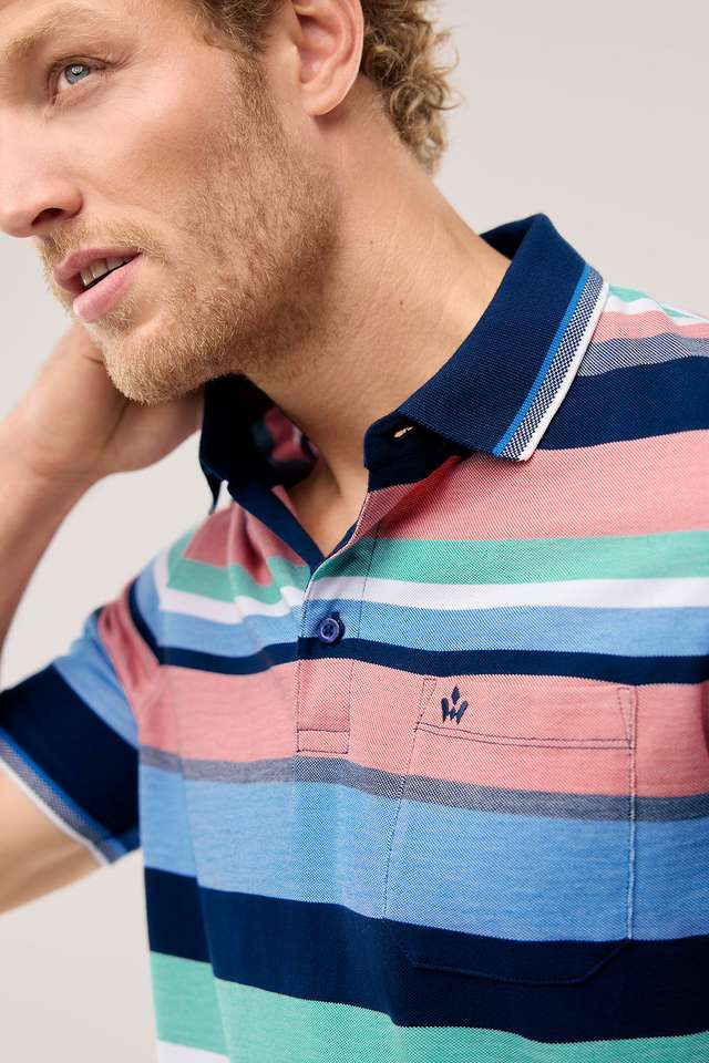 Mann mit lockigem Haar trägt ein bunt gestreiftes Polohemd in Blau, Rosa und Grün und blickt zur Seite. Angezeigt beim Hover